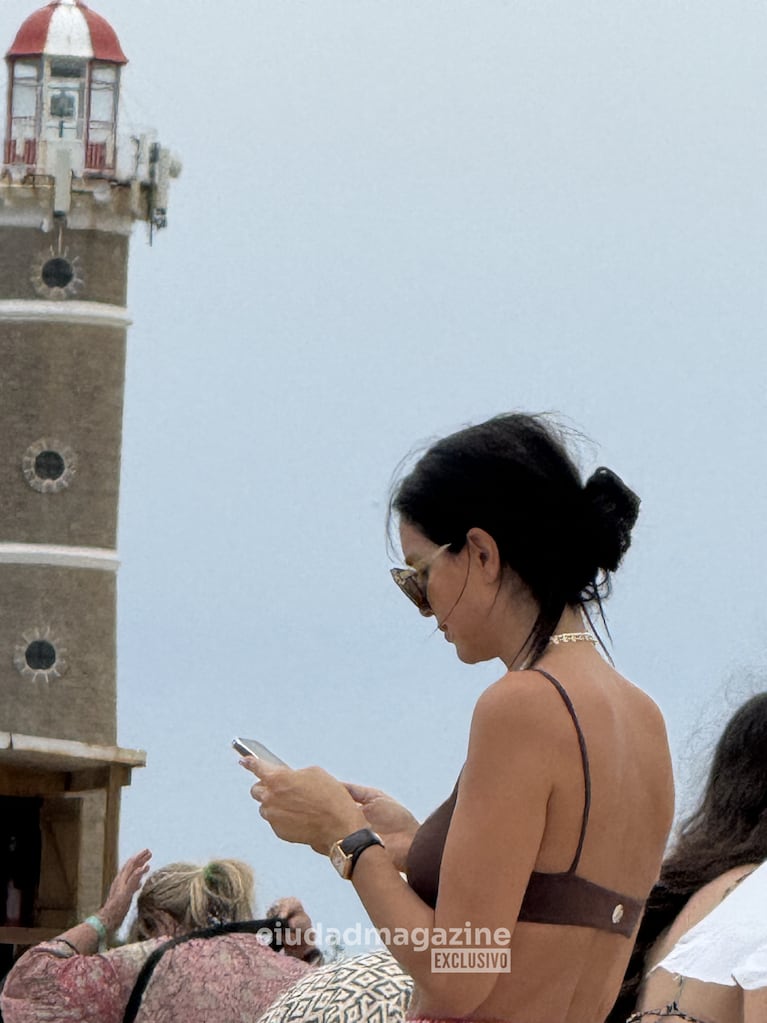 Zaira Nara revisa su celular frente al faro de José Ignacio. Foto: RS Fotos.